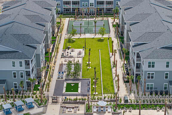 A large grassy area surrounded by buildings with a basketball court in the middle.