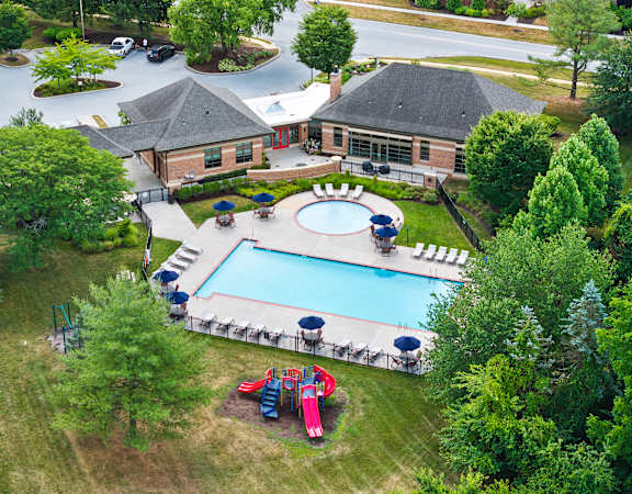 An aerial view of a pool surrounded by trees and a building.