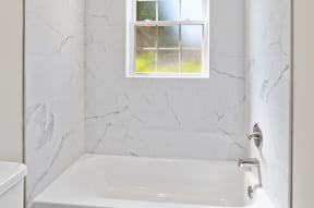 a white bathroom with a white toilet and a white bathtub