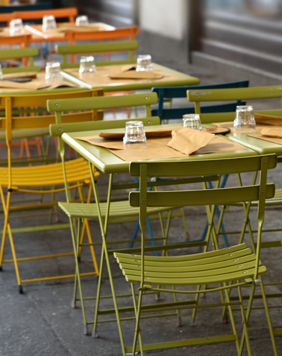 a row of tables and chairs with green chairs at Haven Park, 92411