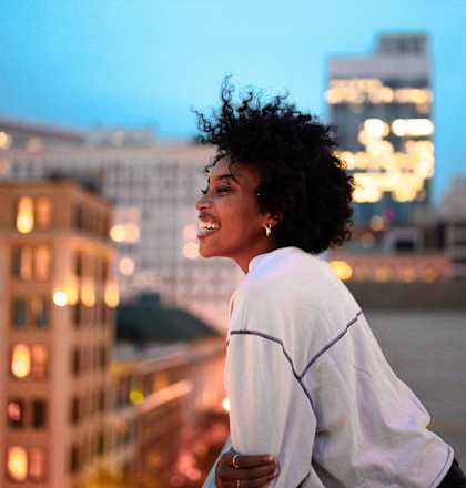 a woman standing on a balcony overlooking a city at dusk