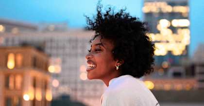 a woman standing on a balcony overlooking a city at dusk