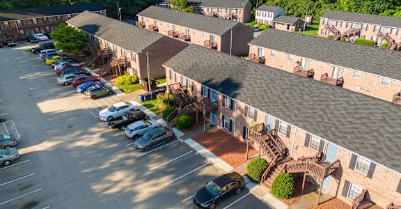 A parking lot with cars and apartment buildings in the background.