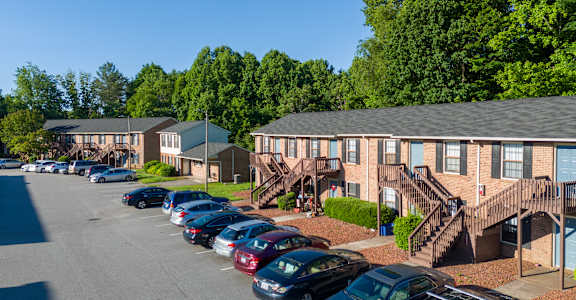 A parking lot with cars and apartment buildings in the background.