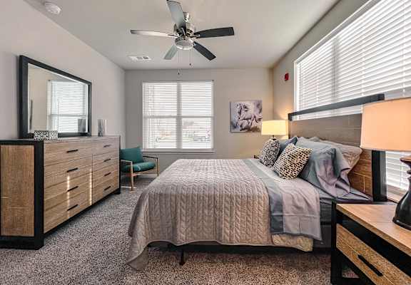 A bedroom with a bed, dresser, and ceiling fan.