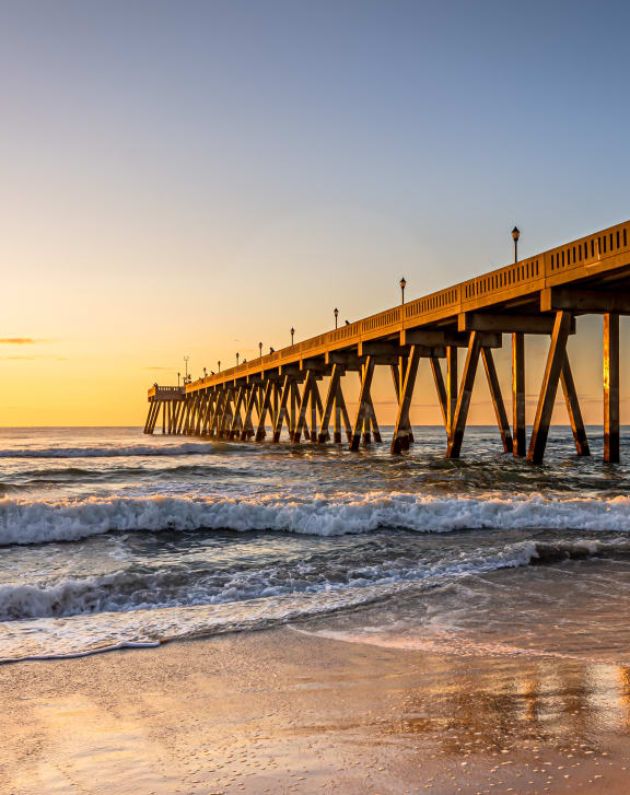 a pier on the beach at sunset