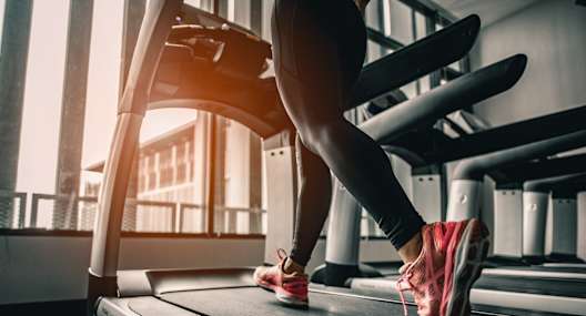 A person is running on a treadmill in a gym.