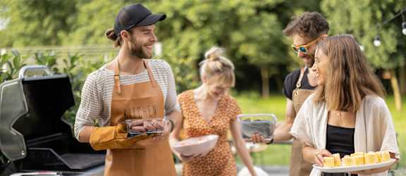A man in an apron is grilling food for a group of people.