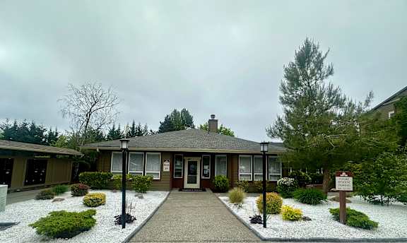 The image shows a building with a brown door and a sign in front of it.