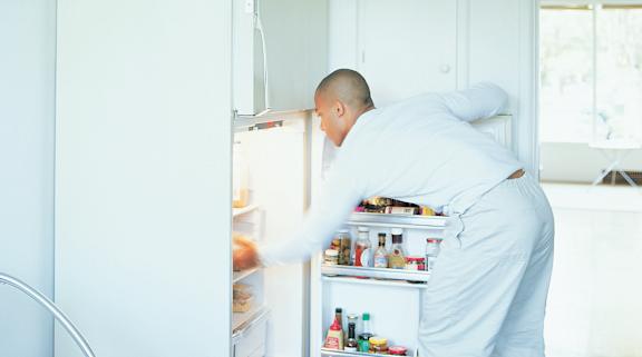 A man in white is opening a white fridge. at University Landing Apartments, Silver Spring, MD