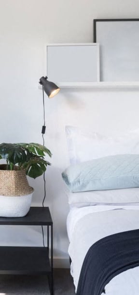 a white bedroom with a bed and a black nightstand