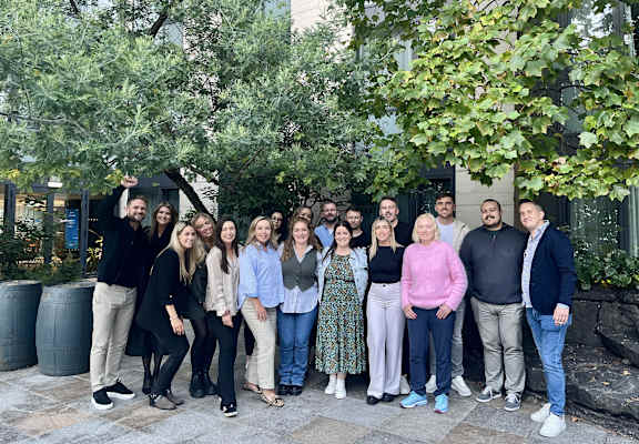 A group of people are standing in front of a tree.