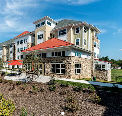 A large building with a red roof is surrounded by a garden. at Rainier Manor Apartments, Maryland