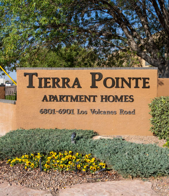 a sign for terra pointe apartment homes in front of a sidewalk and plants