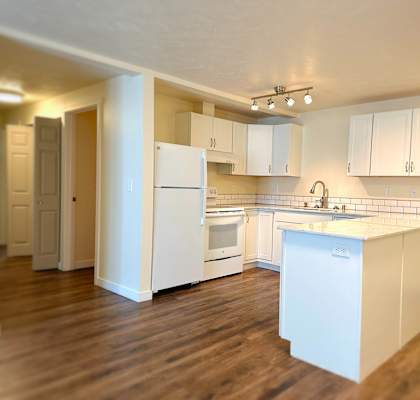 a large kitchen with white appliances and a wooden floor