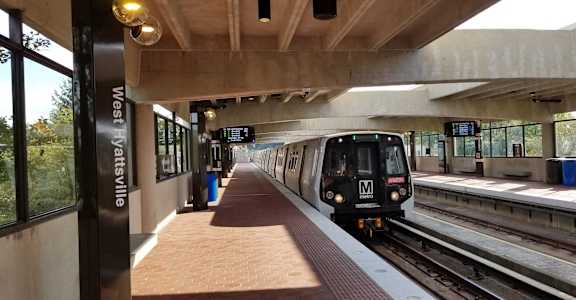 a train pulling into a platform at a train station at Hamilton Manor Apartments, Hyattsville, MD