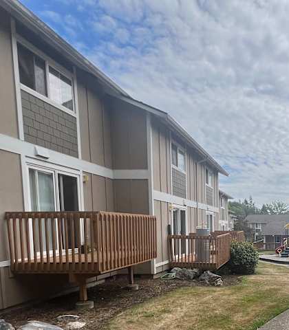 A pathway leads through a grassy area between two rows of apartment buildings.