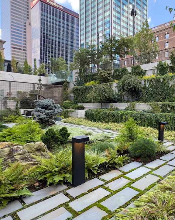 A garden with a stone pathway and a metal post.