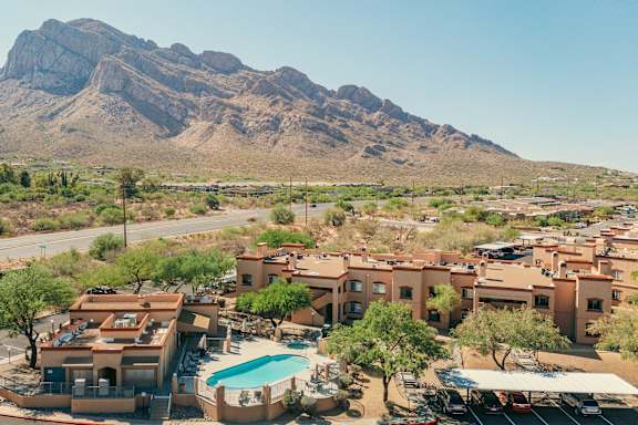 A mountain is behind a building with a pool.