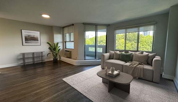 A living room with a grey sofa, a wooden coffee table, and a dining table set up in the background.