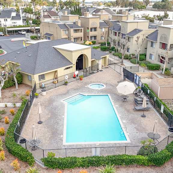 A swimming pool surrounded by a fence and a building in the background.