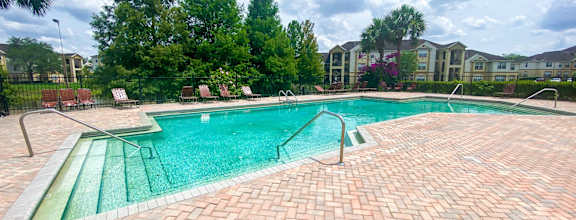 A large outdoor swimming pool surrounded by a brick patio.