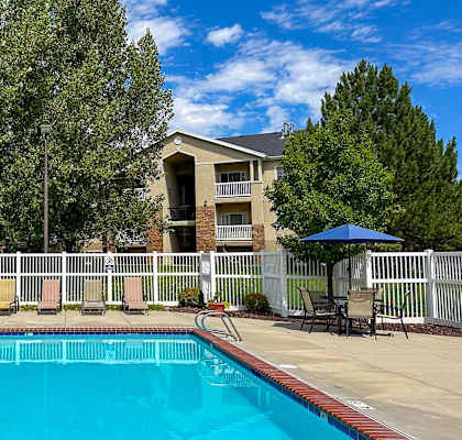A swimming pool surrounded by a white fence and trees.