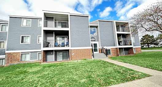 a view of an apartment building with a sidewalk and grass