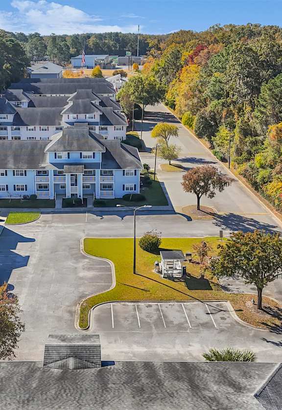 A large white building surrounded by trees in autumn.