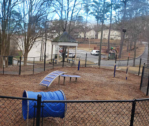 A playground with a blue slide and a black fence.