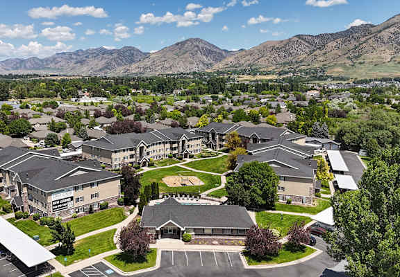 A large building complex with a parking lot in front and mountains in the background.