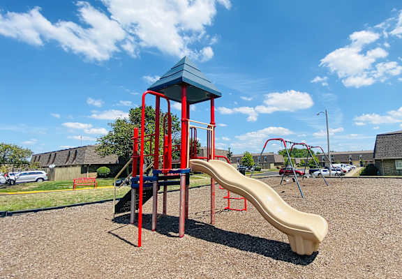 A playground with a red and blue structure and a yellow slide.