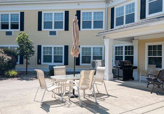 A patio with a table and chairs and an umbrella.