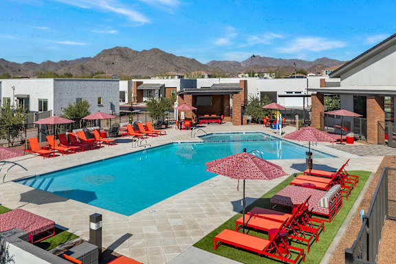 a swimming pool with lounge chairs and umbrellas at the retreat at thousand oaks apartments