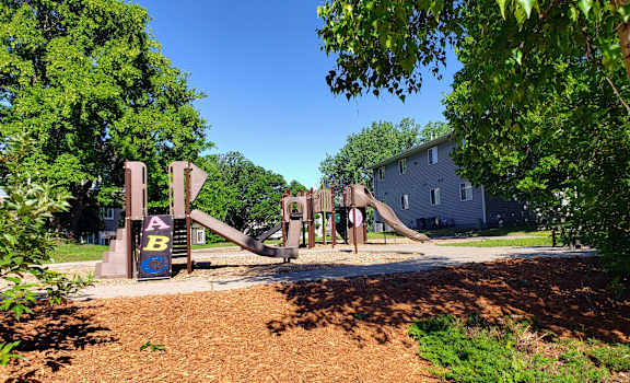 a playground with a set of slides in front of a house