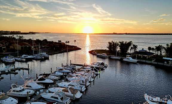 the sun sets over a marina filled with boats at The Ashlar, Fort Myers, FL, 33907