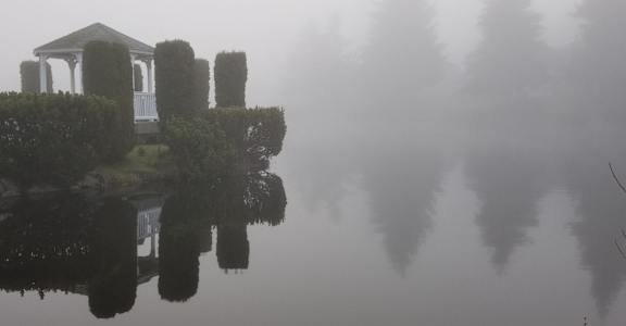 a boat house in the fog on the water