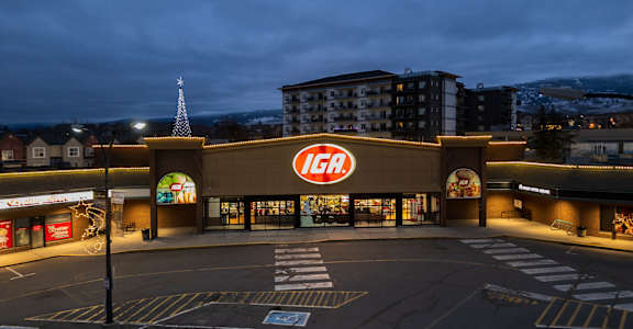 A large IGA store is lit up at night.