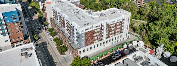 A large white building with a red roof is surrounded by trees and other buildings. at Wilmington Flats Apartments, Salt Lake City, UT, 84106