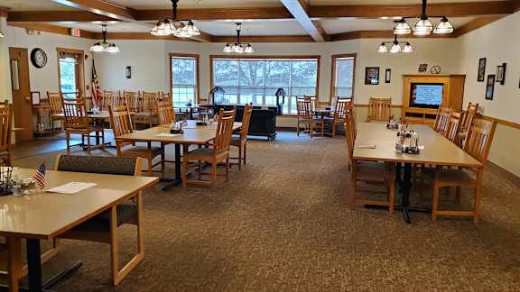 A room with tables and chairs and a television.
