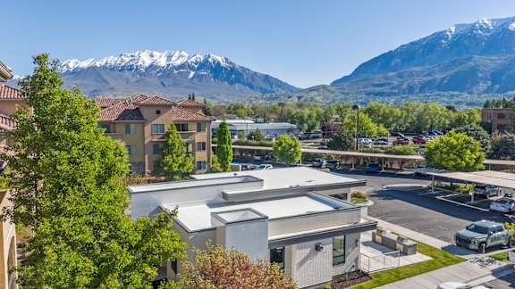 A parking lot in front of a building with a mountain in the background.