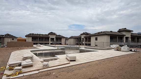 A construction site with unfinished buildings and a pool.