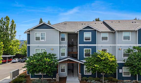 A multi-story apartment building with a parking lot in front.