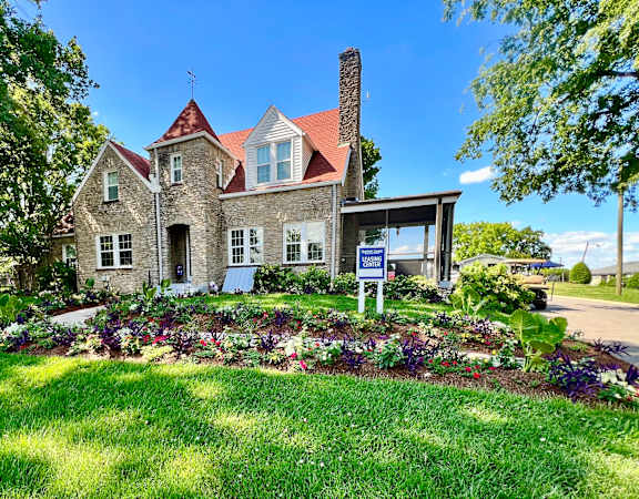 the front yard of a stone house with a flower garden
