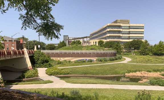 a path leading to a bridge over a pond with a building in the background