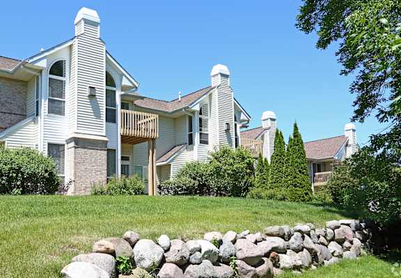 A house with a white exterior and a stone wall in front.