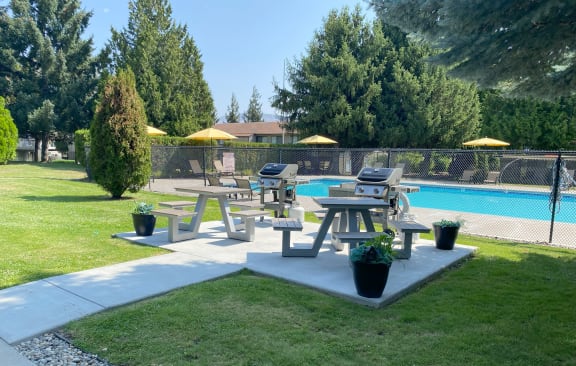 a group of picnic tables in a park next to a pool at Cedarwood, Wenatchee, WA