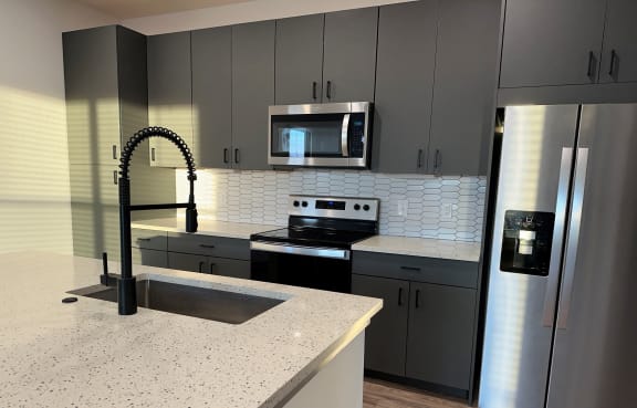 a kitchen with granite counter tops and stainless steel appliances at The Depot, Raymore, MO, 64083