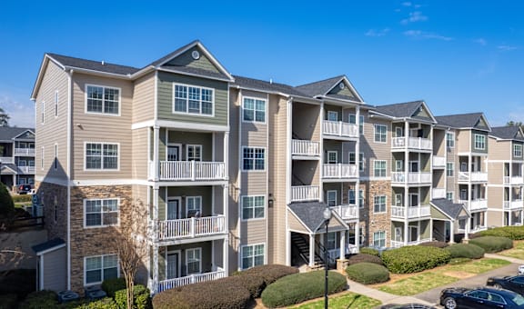 Apartment complex with multiple buildings and cars parked in the driveway.