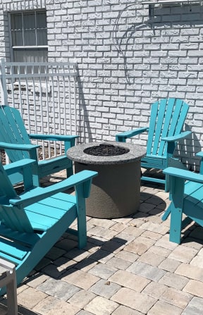 a patio with blue adirondack chairs and a fire pit